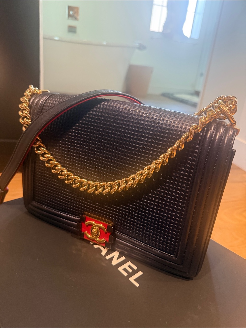 CHANEL Black Leather Shoulder Bag with Gold Chain and Red Accent